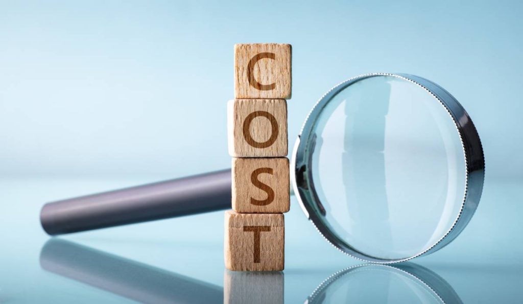 Wooden blocks spelling the word cost with a magnifying glass