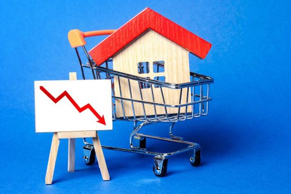 A miniature house in a shopping cart with a downward trend(to show mortgage rates forecast) on a blue background.