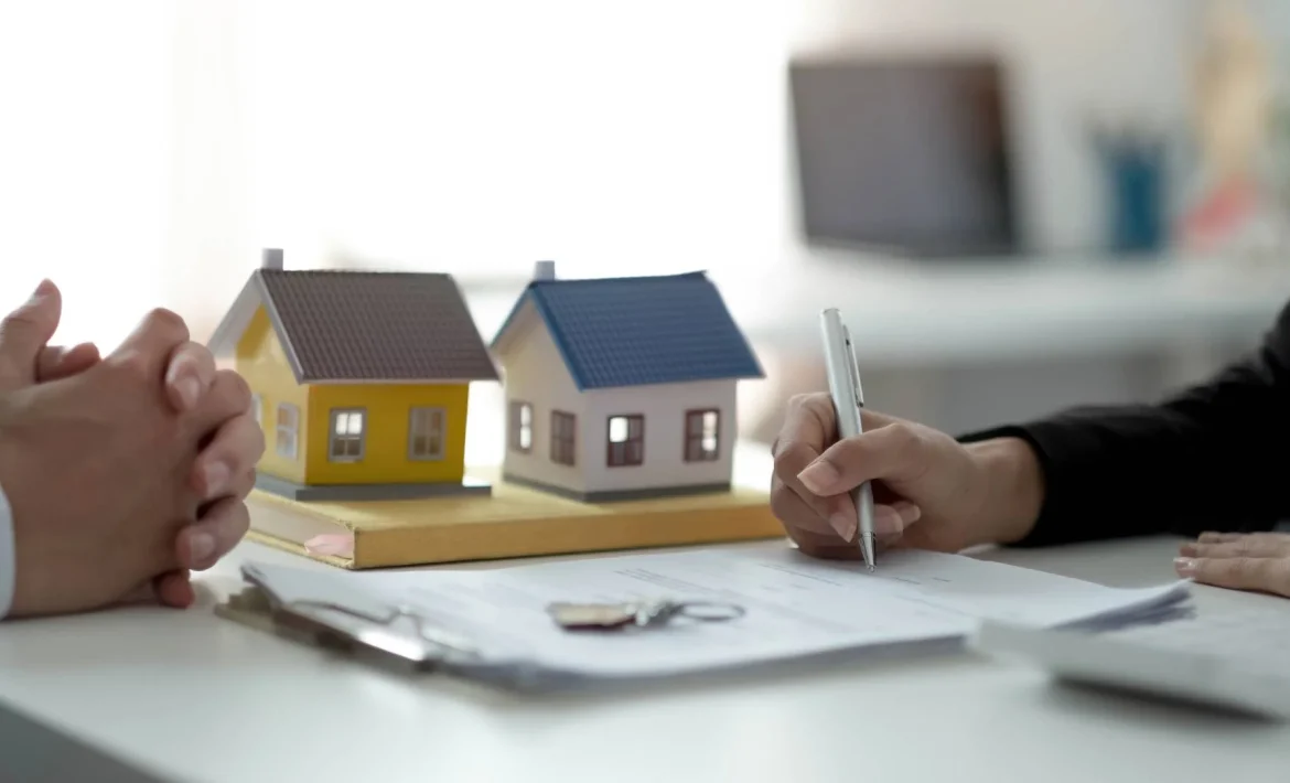 two people sitting at a table with a house model in front of them